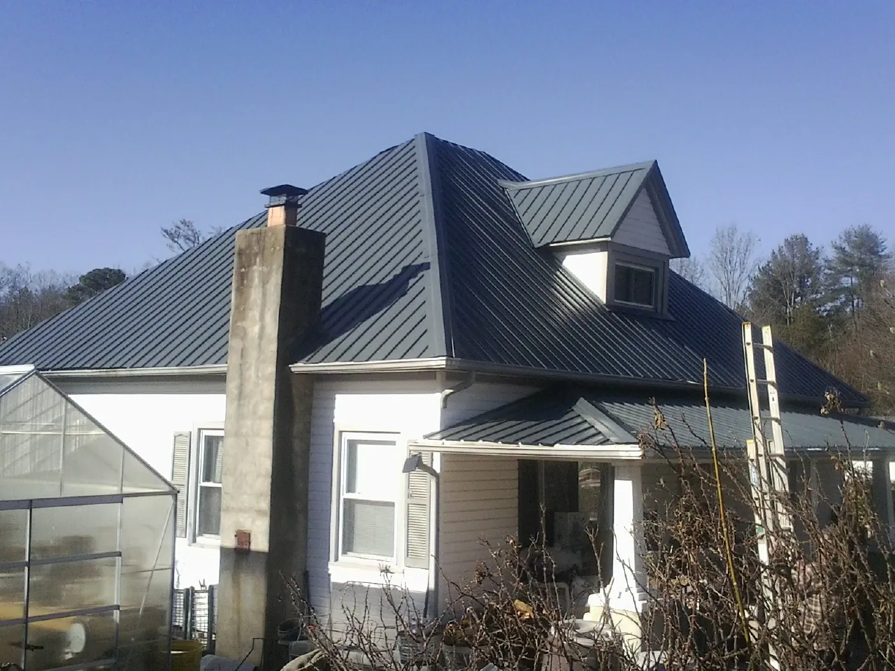 Dark blue standing seam metal roof on a white farmhouse with dormer — Slate & Tile Roof Repair by Roofing Brothers in Cumberland Gap