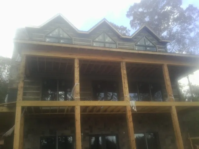 Dormers and porch framing on a large log home under construction — Roof Coating work by our crew in Cumberland Gap