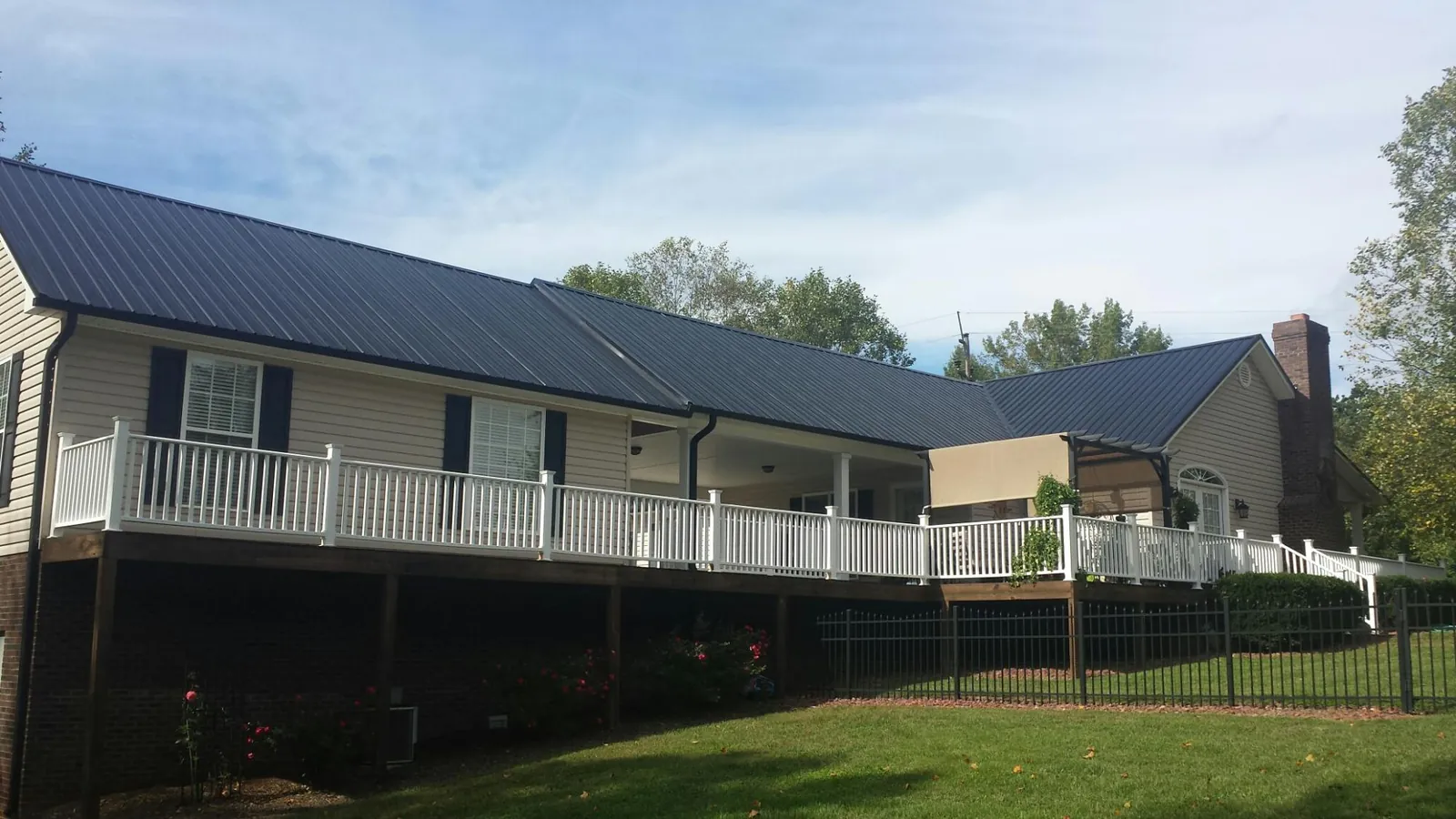 Black metal roof above a long white railed deck on a hillside home in Cumberland Gap